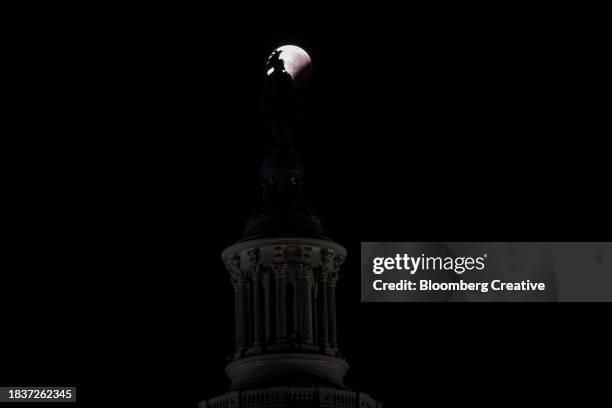 a lunar eclipse behind the statue of freedom - capitol hill winter stock pictures, royalty-free photos & images