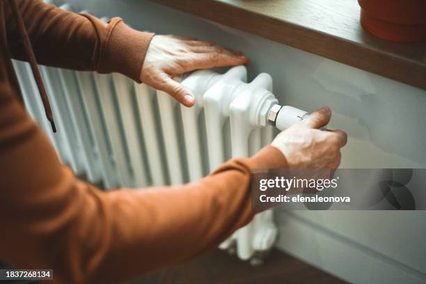 mature adult man warms himself by the radiator in the room - feber bildbanksfoton och bilder