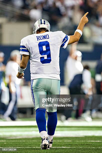 Tony Romo of the Dallas Cowboys signals while walking off the field after throwing a touchdown pass against the Denver Broncos at AT&T Stadium on...