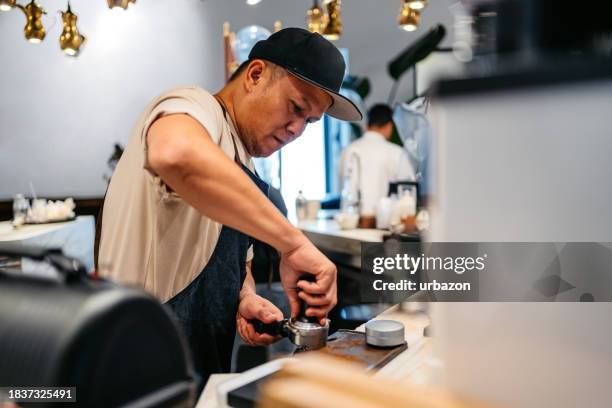 young barista grinding coffee beans to make coffee in a coffee shop in kuwait - distillery still stock pictures, royalty-free photos & images