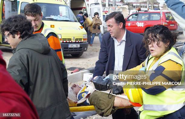 Rescue workers evacuate an injured person in front of a destroyed train at the Atocha railway station in Madrid 11 March 2004. At least 72 people...