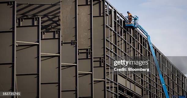 Worker continues construction in a cherry picker on a building to be used for ship manufacturing at the Seaspan Vancouver Shipyard in North...