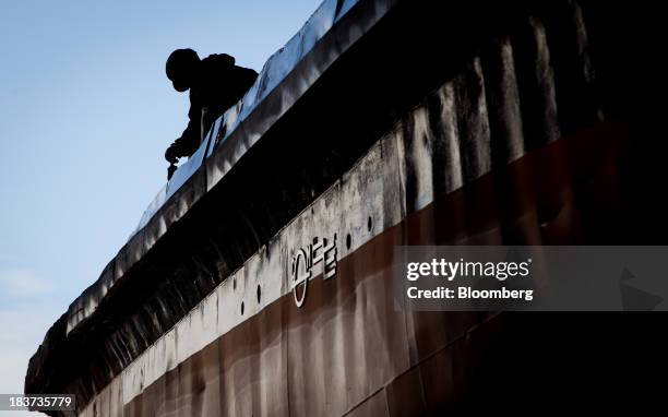 The silhouette of a worker is seen painting the Pacer tugboat as it undergoes repairs at the Seaspan Vancouver Shipyard in North Vancouver, British...