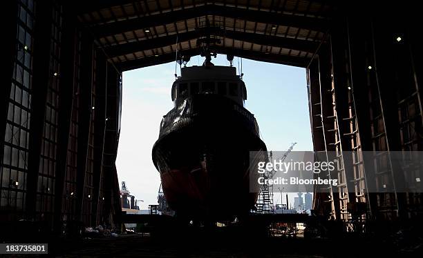 The silhouette of a worker is seen climbing scaffolding to board the Pacer tugboat as it undergoes repairs at the Seaspan Vancouver Shipyard in North...