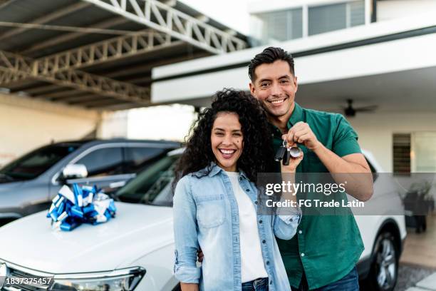 portrait d’un couple d’adultes faisant la fête après l’achat d’une voiture chez un concessionnaire - nouveauté photos et images de collection