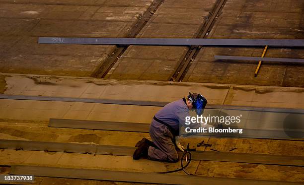 Worker uses a mallet while welding a portion of a barge under construction at the Seaspan Vancouver Shipyard in North Vancouver, British Columbia,...