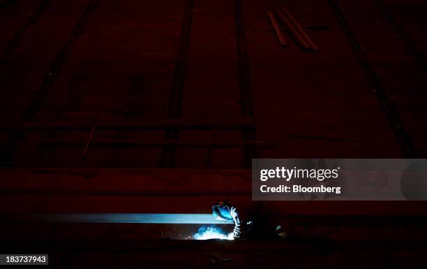 Worker welds a portion of a barge under construction at the Seaspan Vancouver Shipyard in North Vancouver, British Columbia, Canada, on Wednesday,...