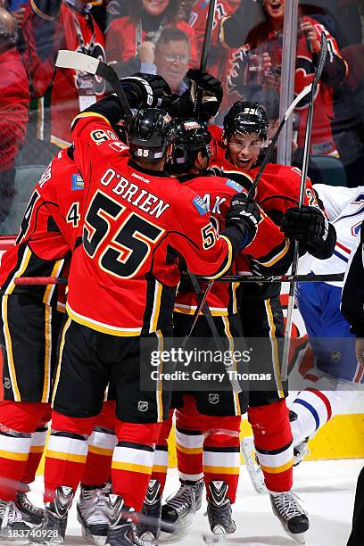 Sean Monahan, Shane O'Brien and teammates of the Calgary Flames celebrate a goal against the Montreal Canadiens at Scotiabank Saddledome on October...