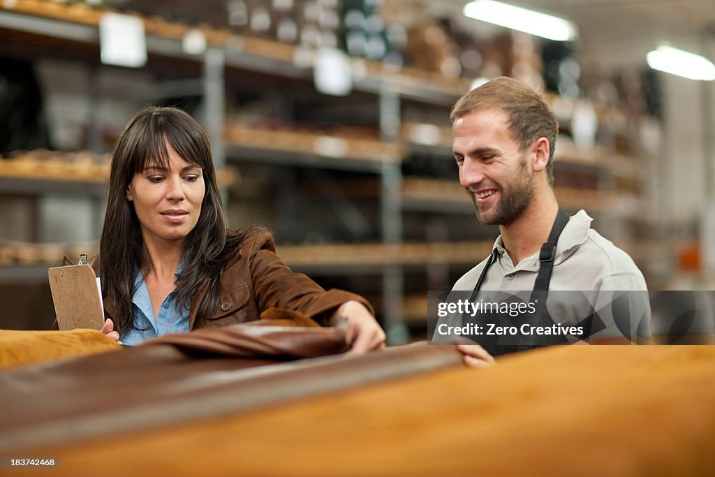 Worker and manager looking at roll of leather