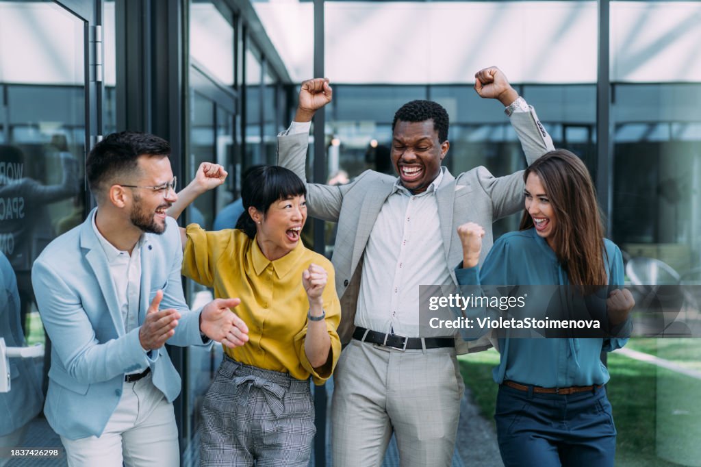 Cheerful entrepreneurs celebrating success in the office.