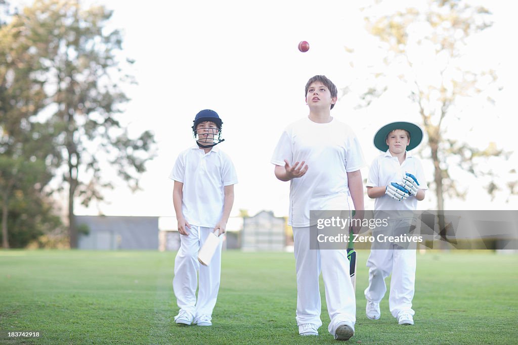 Three boys walking on cricket pitch