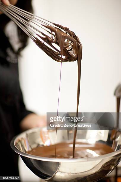 woman with mixing bowl and melted chocolate - ballonklopper stockfoto's en -beelden