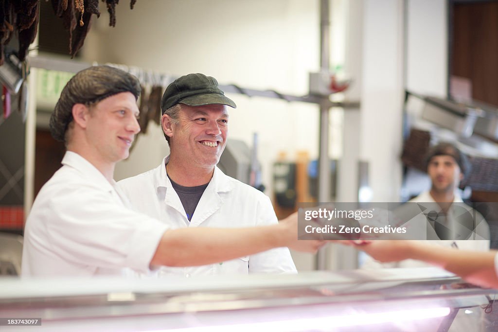 Men serving customer on butcher's counter