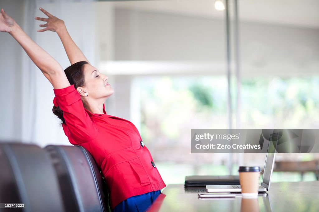 Young woman in office stretching