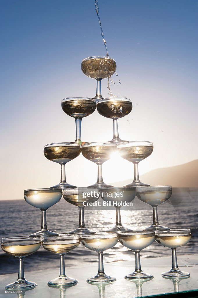 Champagne pouring into glasses with sea in background