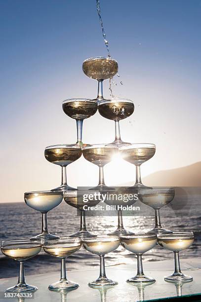 champagne pouring into glasses with sea in background - champagne pyramid stock pictures, royalty-free photos & images