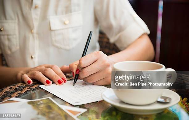 woman writing postcard in cafe - ansichtskaart stockfoto's en -beelden