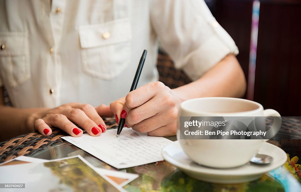 Woman writing postcard in cafe