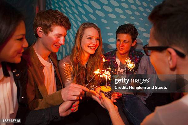 group of teenagers sitting around birthday cake with sparklers - boy party photos et images de collection