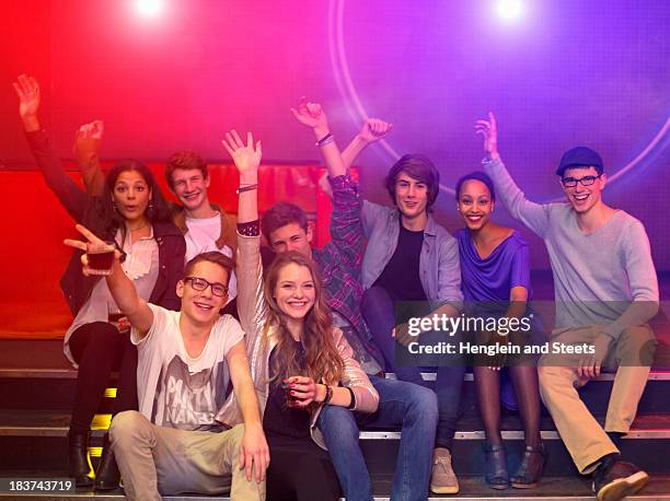 group of teenagers and young adults at party holding drinks and raising arms - teenage girl club stock-fotos und bilder