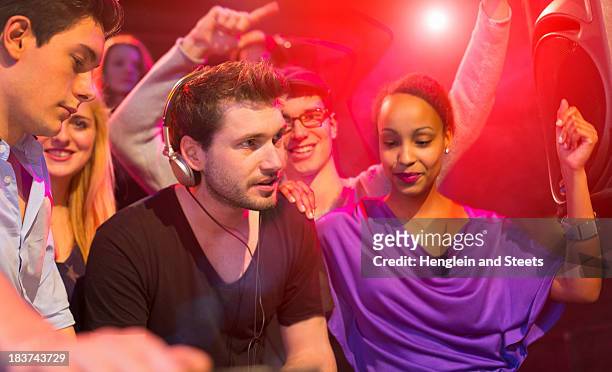 group of people dancing at party, man wearing headphones - girl dj stock-fotos und bilder