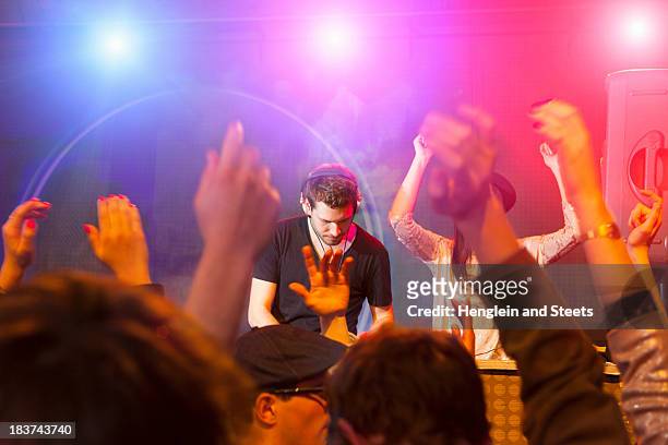 disc jockey surrounded by raised arms - dj club stock pictures, royalty-free photos & images