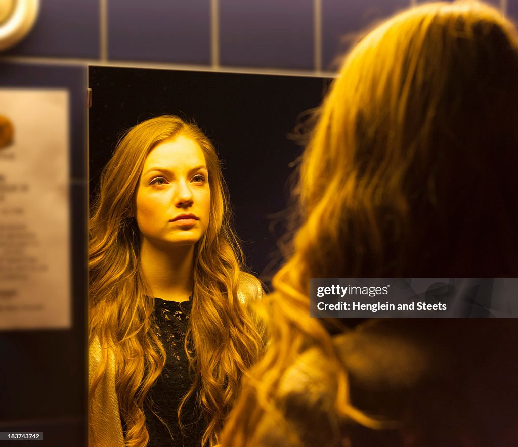 Teenage girl looking at her reflection in mirror