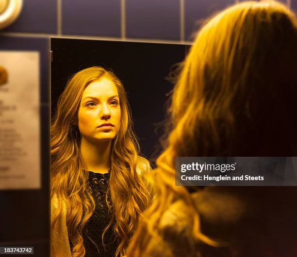 teenage girl looking at her reflection in mirror - nightclub bathroom stockfoto's en -beelden