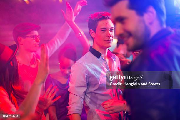 teenage boy surrounded by group of people dancing at party - teenage girl club stock-fotos und bilder