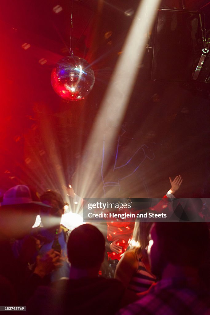 Nightclub scene with people dancing, disco ball, lighting equipment