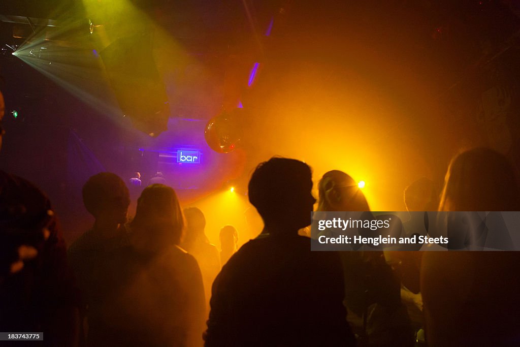 Nightclub scene with people dancing, disco ball, lighting equipment