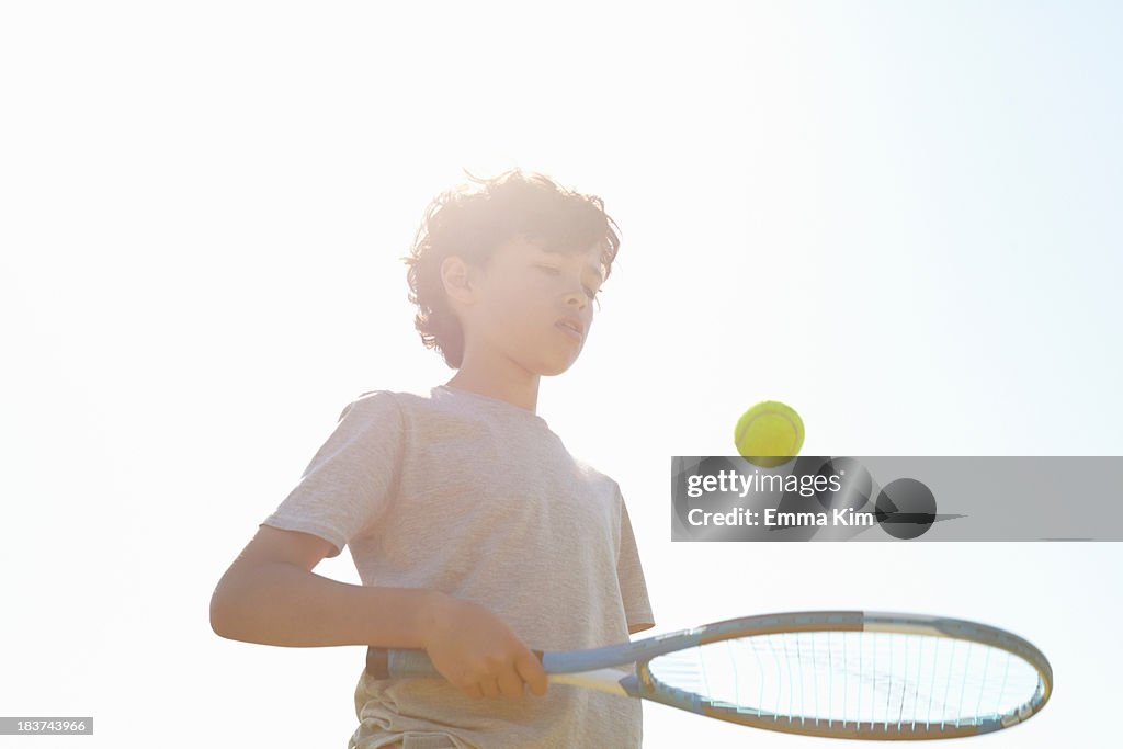 Boy bouncing ball on tennis racket