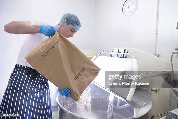 baker pouring flour from sack into mixer - flour bag stockfoto's en -beelden