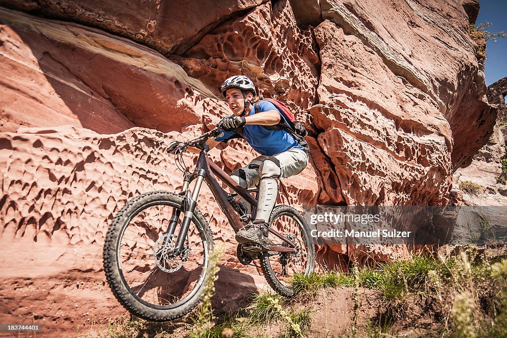 Man mountain biking next to rocks