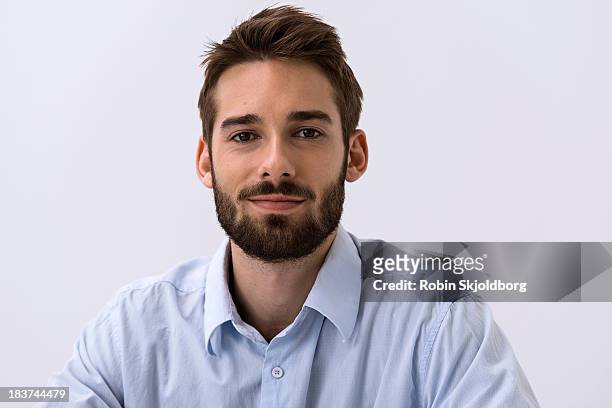 close up portrait of young man in blue shirt - dunkelhaariger mann stock-fotos und bilder