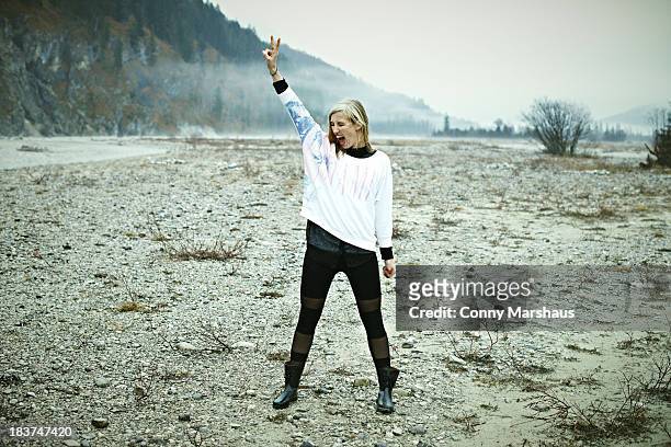 woman standing in remote setting making peace sign - frauenpower stock-fotos und bilder