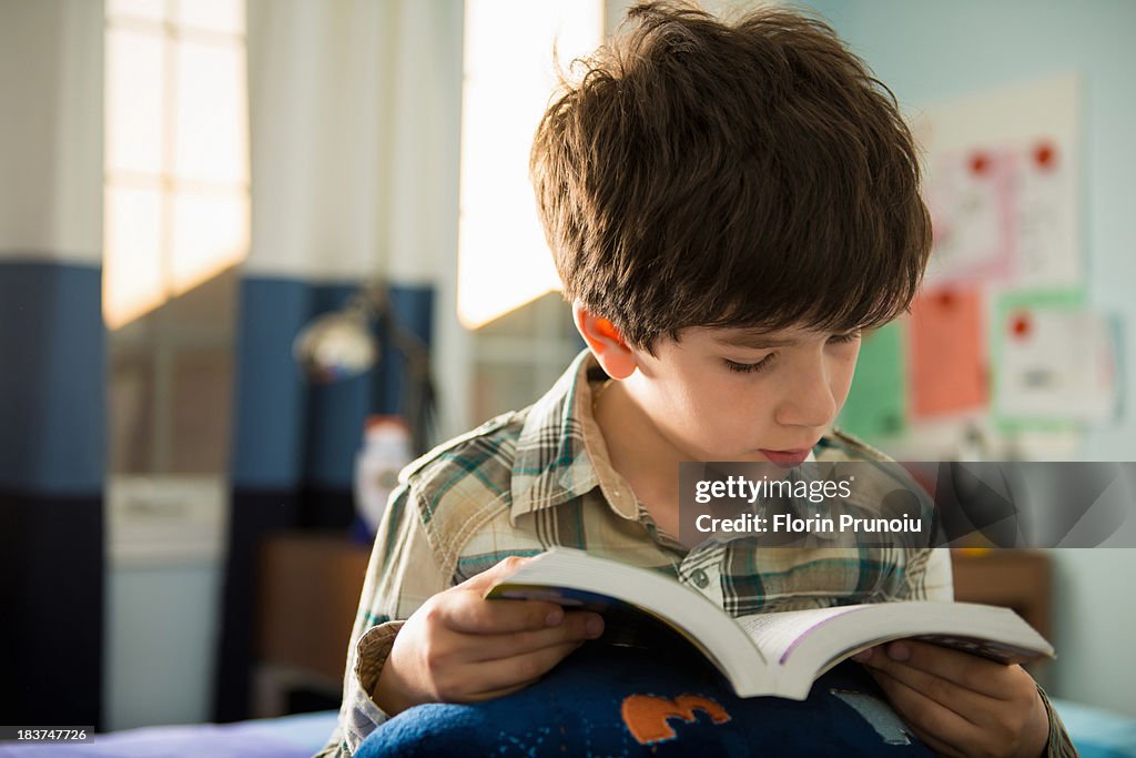 Boy sitting on bed reading book