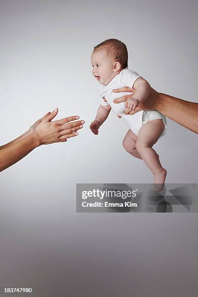 parents passing baby daughter to each other - passing giving stock pictures, royalty-free photos & images