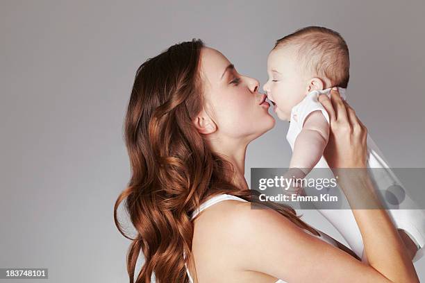 mother kissing baby daughter - baby studio shot stock pictures, royalty-free photos & images