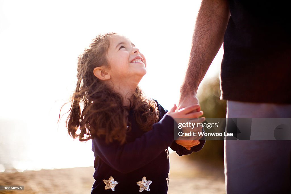 Girl holding father's hand, looking up