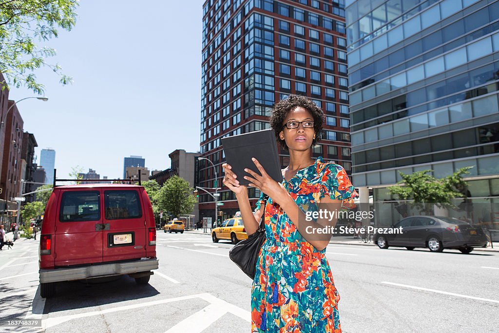 Woman on street parking bay holding digital tablet