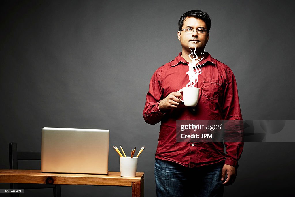 Man holding cup of steaming hot beverage
