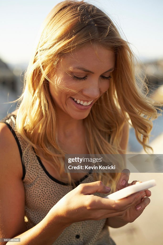 Woman smiling at text message on mobile phone