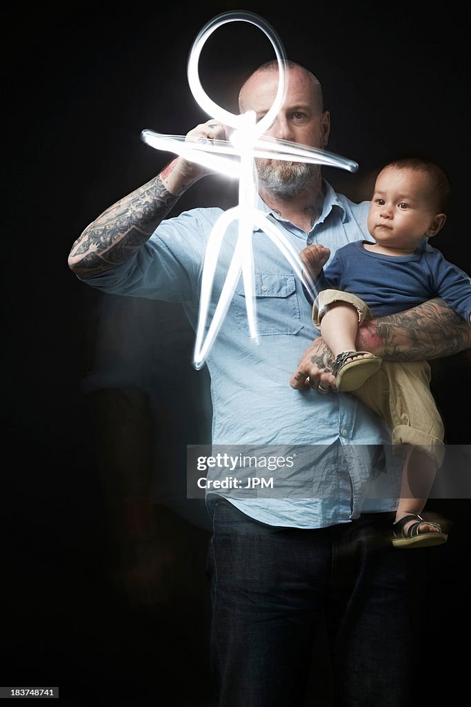 Man drawing to entertain baby in arms