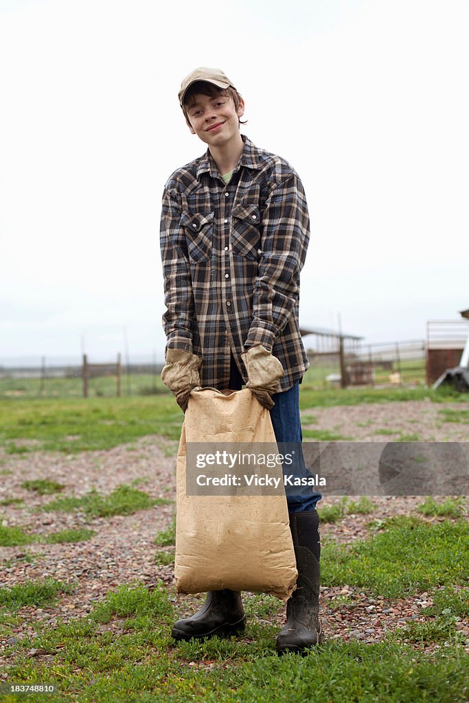 Boy carrying sack of feed