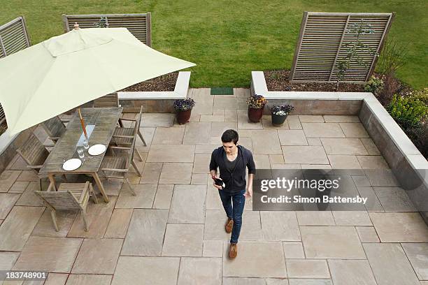 man walking across patio with wine bottle - gartenschirm stock-fotos und bilder