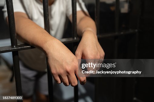 Hands of a prisoner in a cell behind bars. Hands of a prisoner in a cell behind bars.
