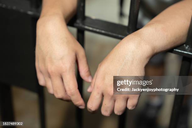 hands of a prisoner in a cell behind bars. - prisioneiro político - fotografias e filmes do acervo