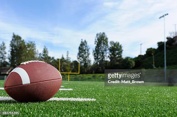 close-up of a football on a field with view of the goalpost - american football field stock pictures, royalty-free photos & images