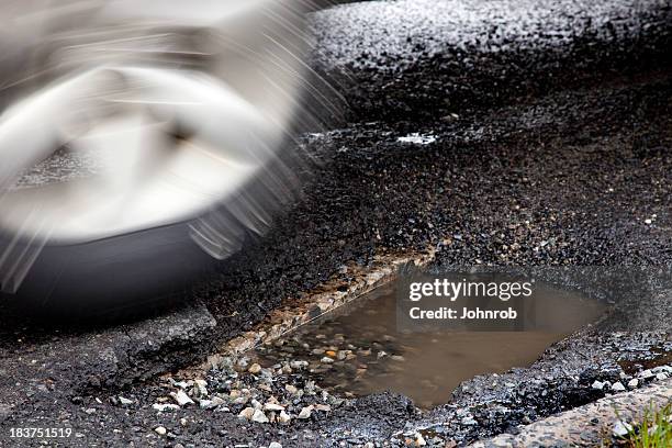 moving auto tire about to enter large pothole, motion blur - aluminiumfälg bildbanksfoton och bilder